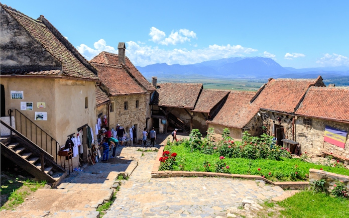 Visitors exploring the historic Rasnov Citadel courtyard with mountain views.