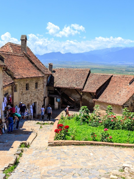 Visitors exploring the historic Rasnov Citadel courtyard with mountain views.