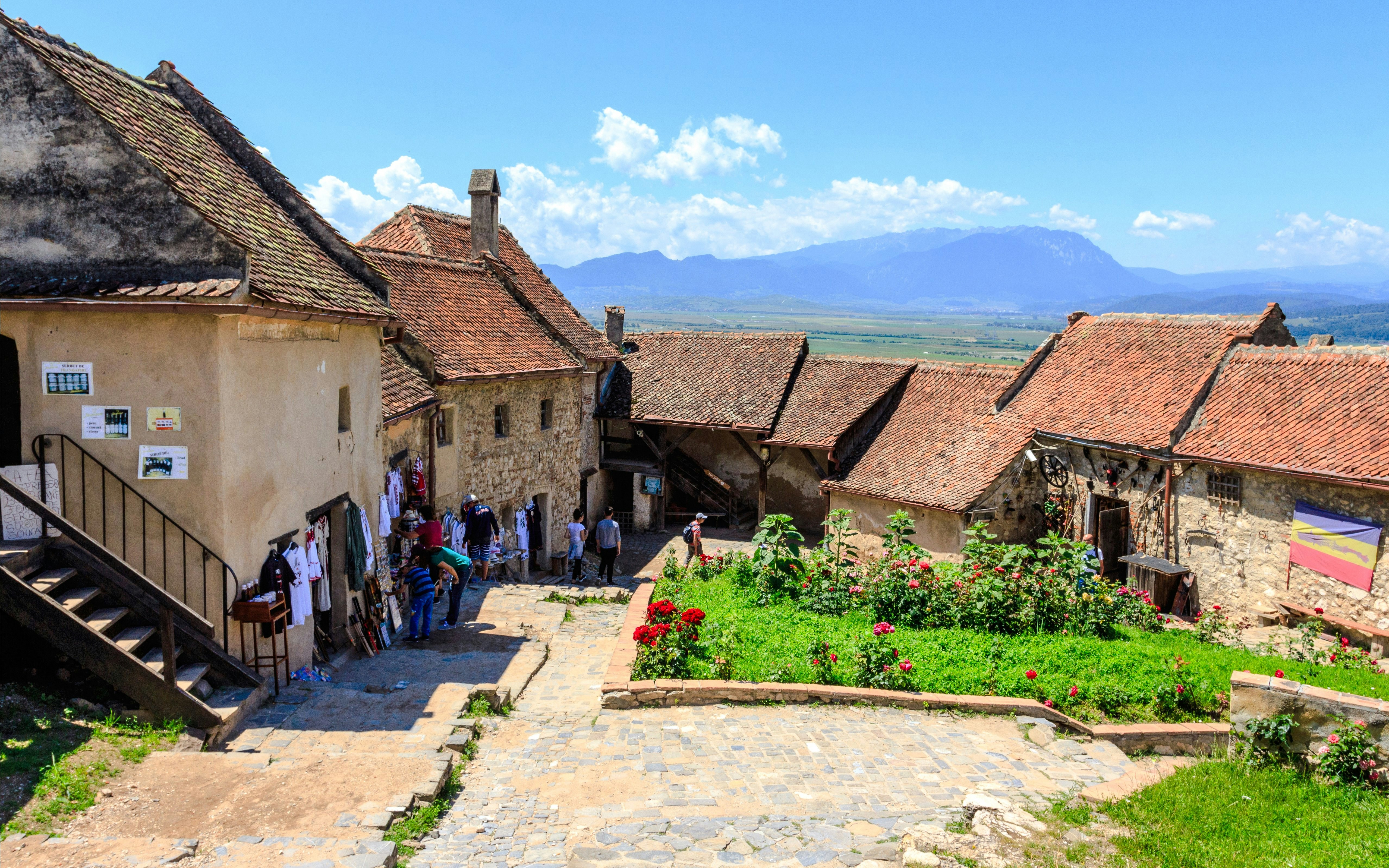 Visitors exploring the historic Rasnov Citadel courtyard with mountain views.