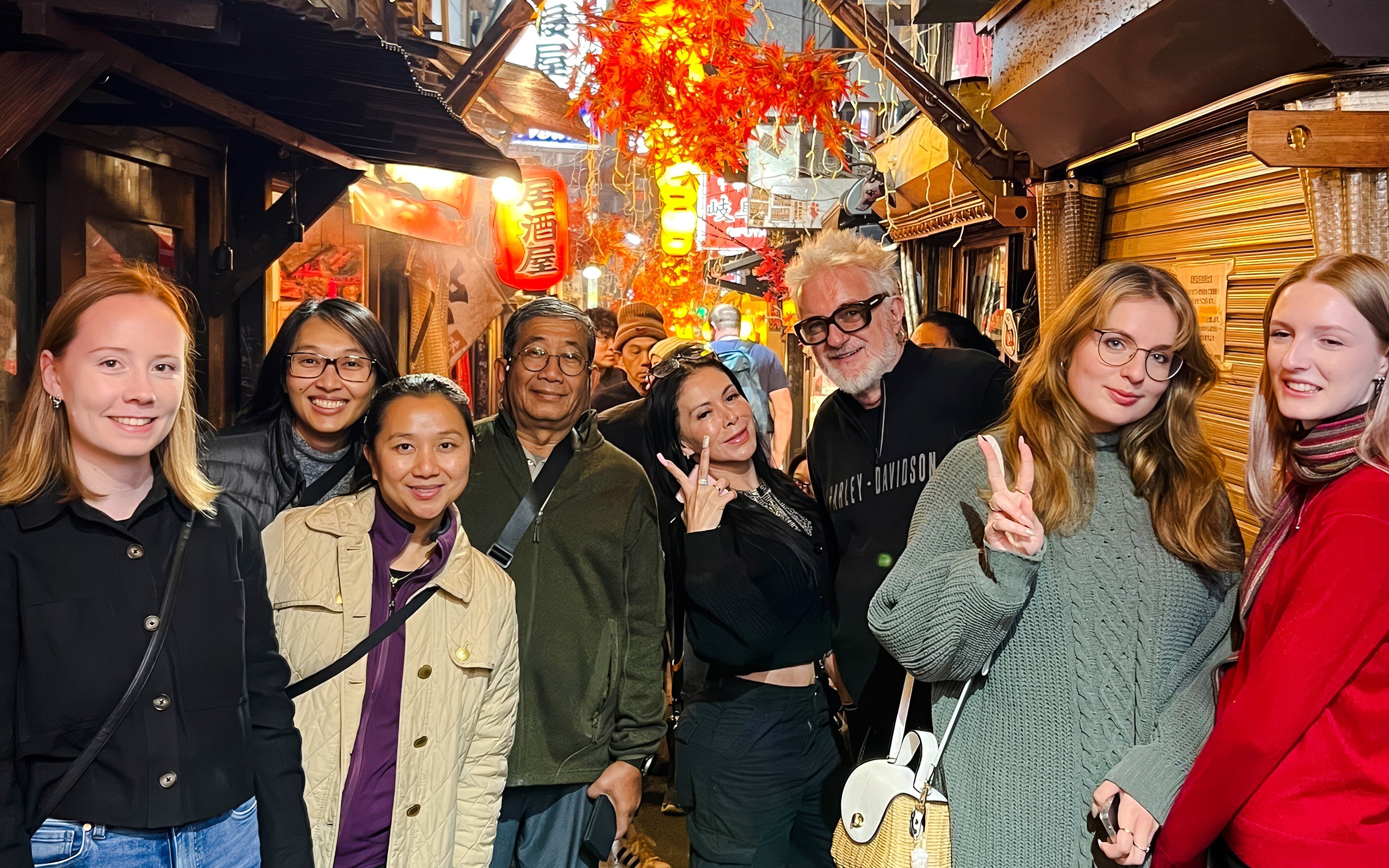 Tourists enjoying Shinjuku food tour in Tokyo, exploring eateries with vibrant street lights.