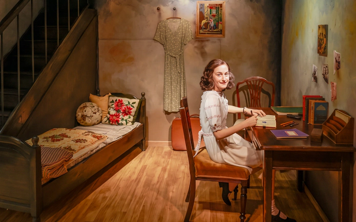 Wax figure of a young woman writing at a desk in Madame Tussauds Vienna.