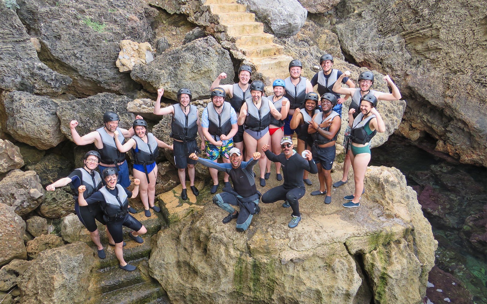 Group of people in life vests on rocky shore, Mallorca, ready for snorkeling and kayaking adventure.