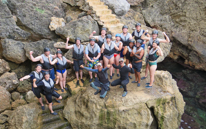 Group of people in life vests on rocky shore, Mallorca, ready for snorkeling and kayaking adventure.
