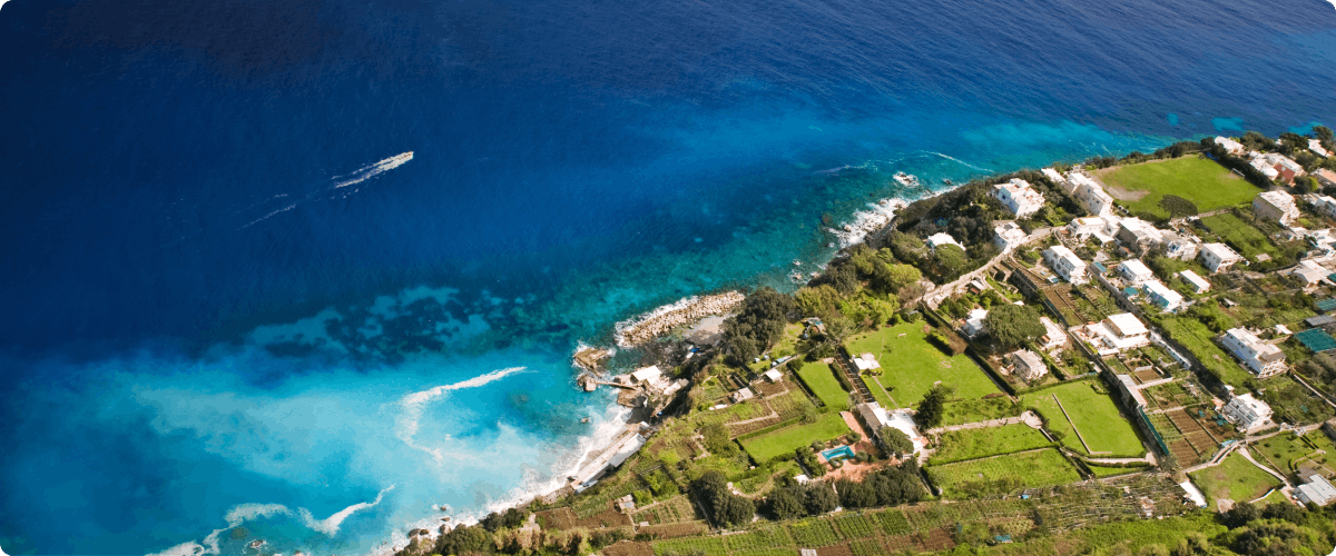 Aerial view of Capri coastline with turquoise waters and lush greenery.