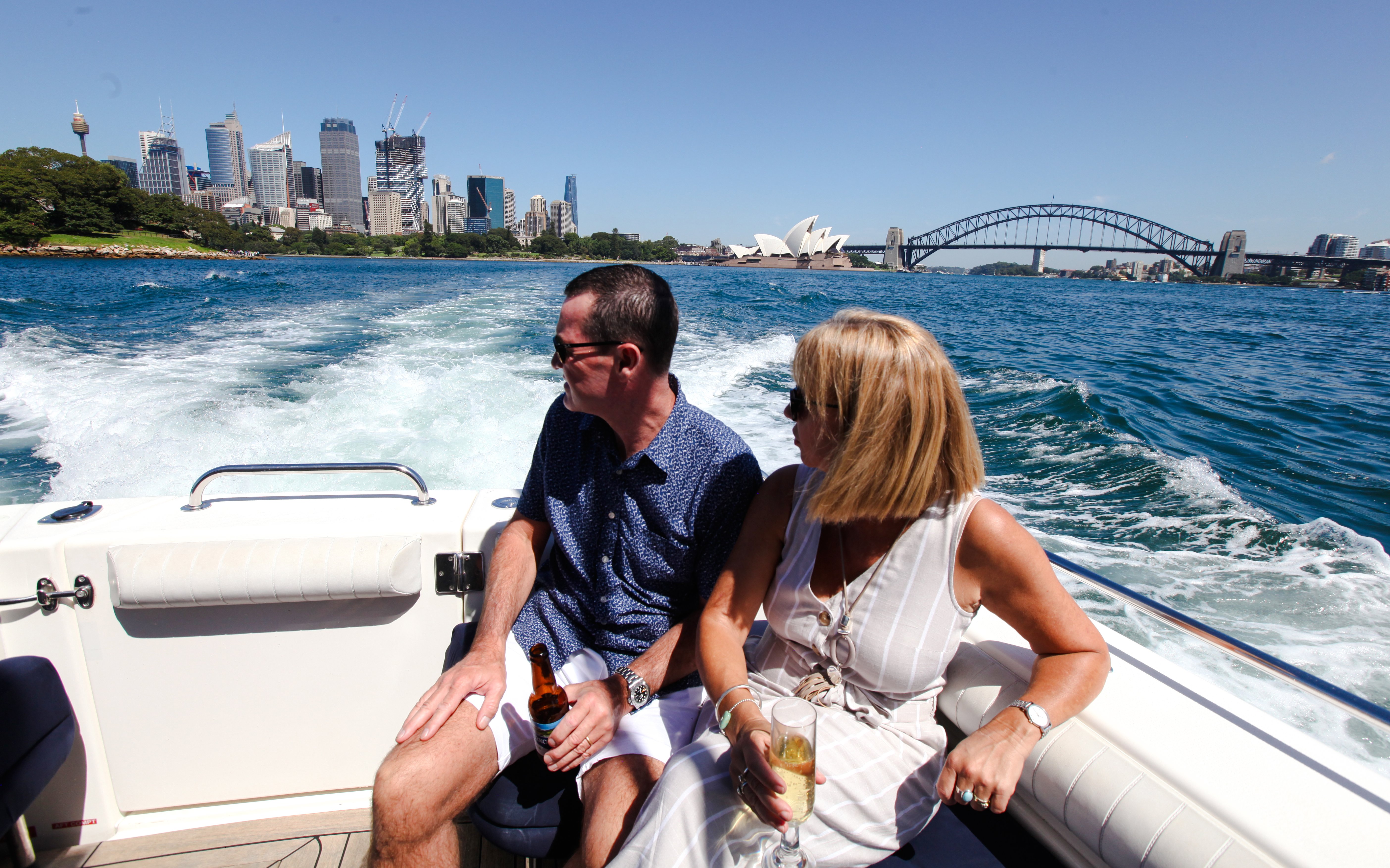 Couple enjoying Sydney Harbour cruise with views of Opera House and Harbour Bridge.