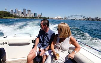 Couple enjoying Sydney Harbour cruise with views of Opera House and Harbour Bridge.