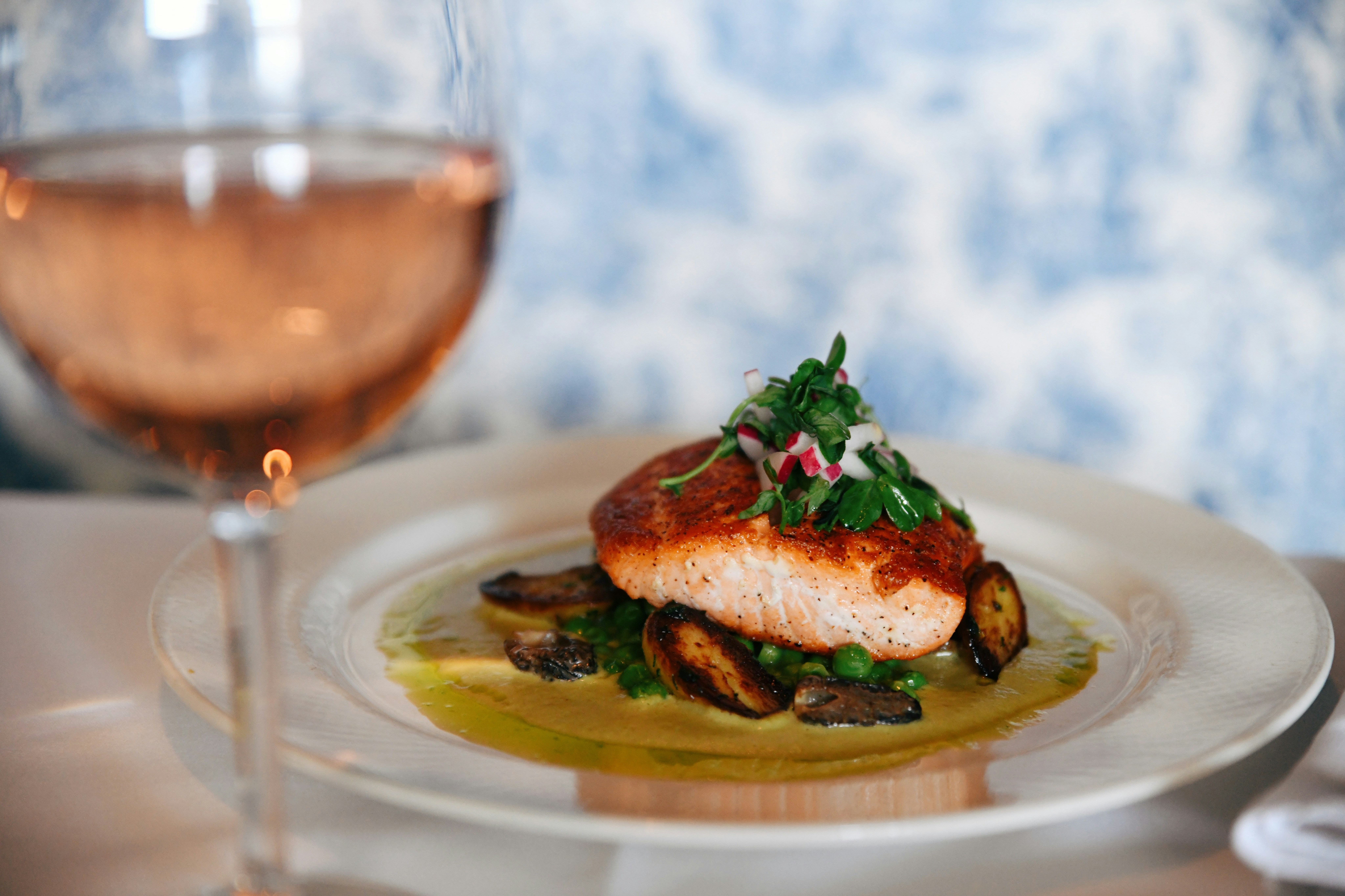 Salmon fillet with greens and mushrooms, French fine dining setting.