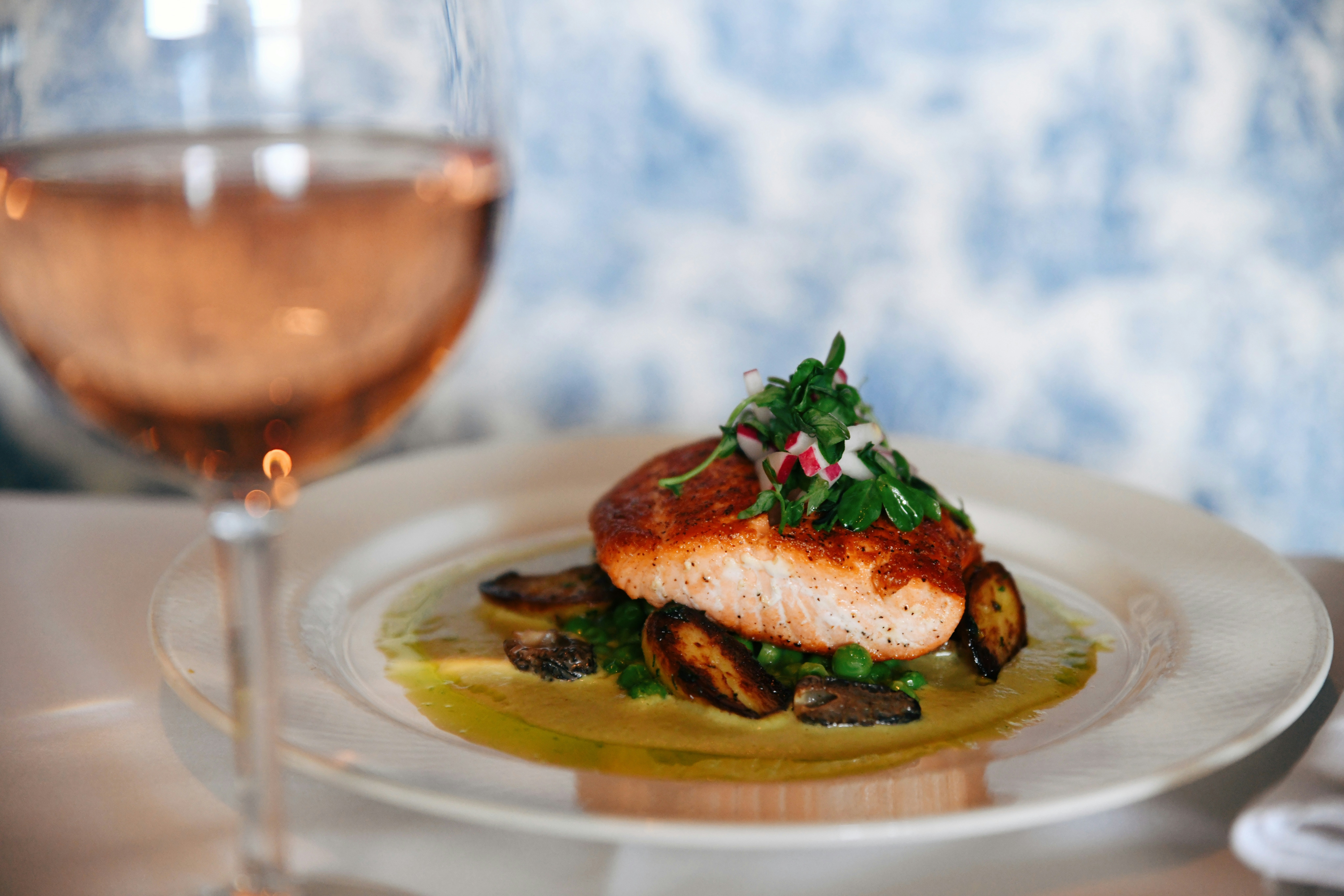 Salmon fillet with greens and mushrooms, French fine dining setting.