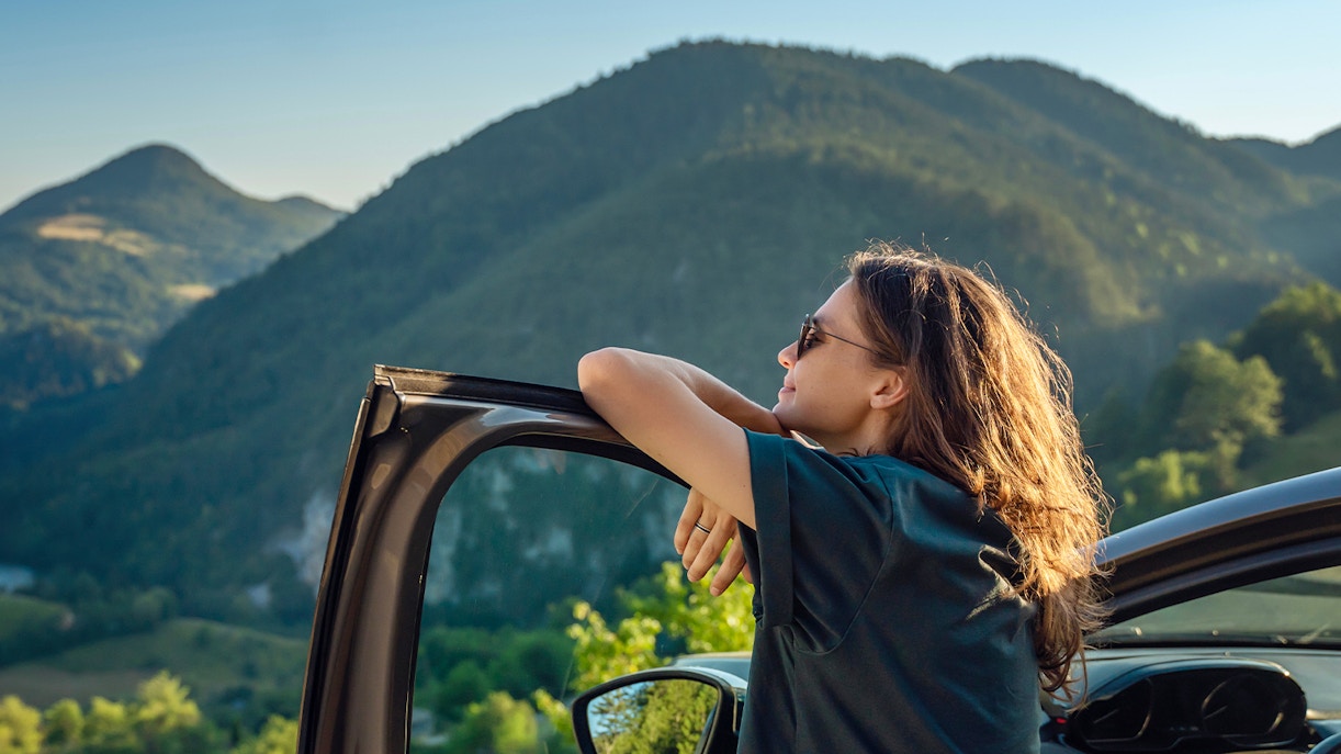 Person enjoying mountain view from car window, ideal for scenic road trips.