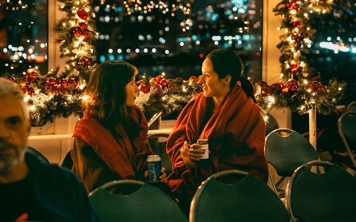 Two people enjoying a festive evening on the Circle Line Harbor Lights Cruise.