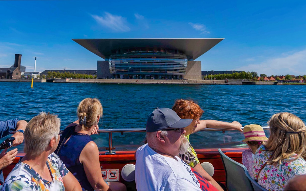 Tourists on a boat viewing the Copenhagen Opera House during a canal tour.