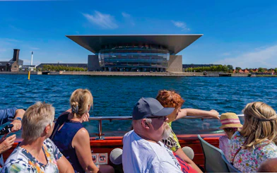 Tourists on a boat viewing the Copenhagen Opera House during a canal tour.