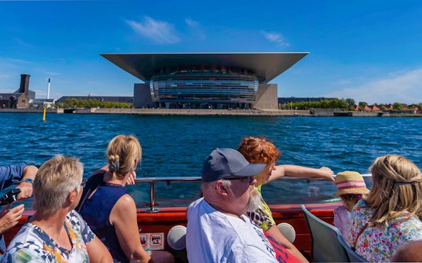 Tourists on a boat viewing the Copenhagen Opera House during a canal tour.