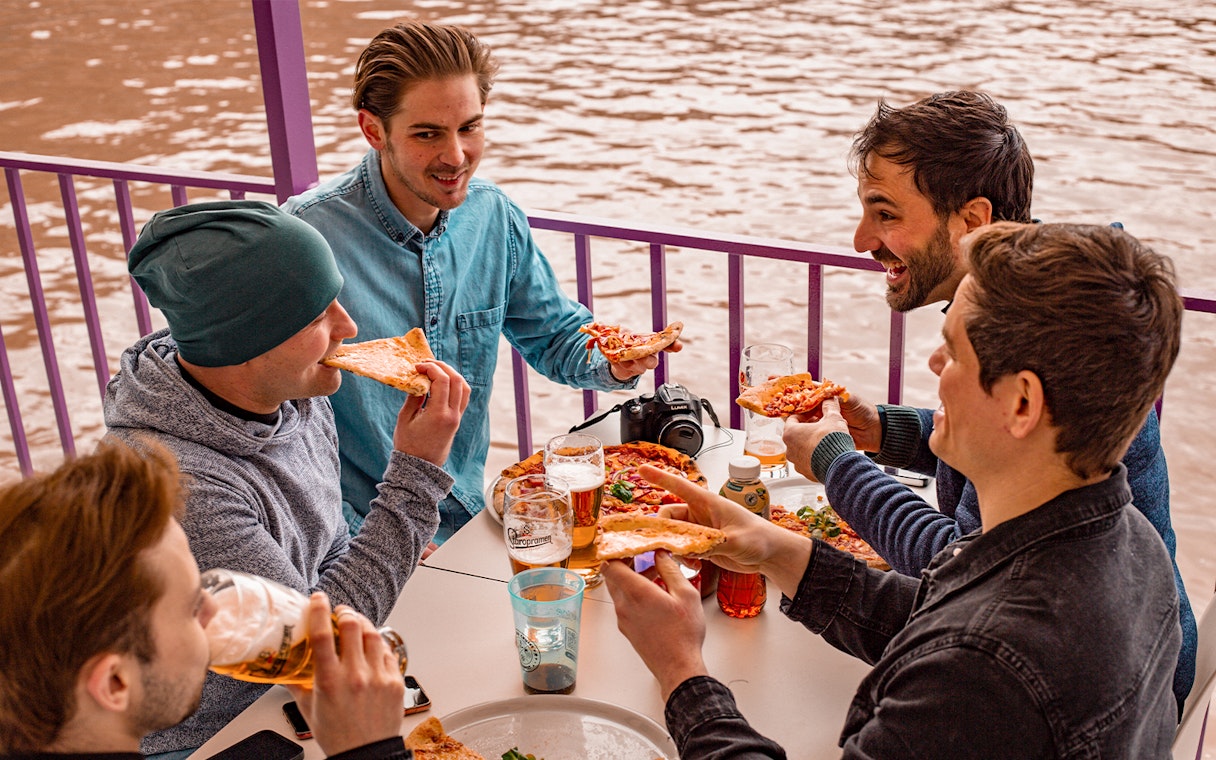 Group enjoying pizza and drinks on a Budapest party boat cruise.