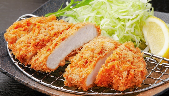 Rosu katsu dish served with shredded cabbage and dipping sauce in Tokyo, Japan.