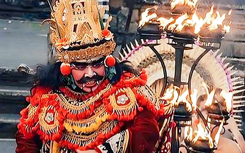 Performer in traditional costume at Ubud Kecak & Fire Dance Show, Bali, with flames in the background.