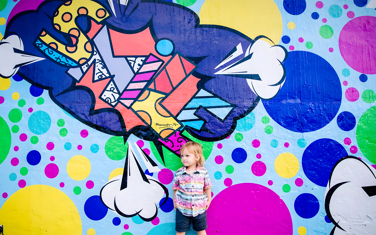 Colorful graffiti mural at Wynwood Walls, Miami, with a child standing in front.