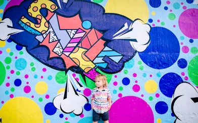 Colorful graffiti mural at Wynwood Walls, Miami, with a child standing in front.