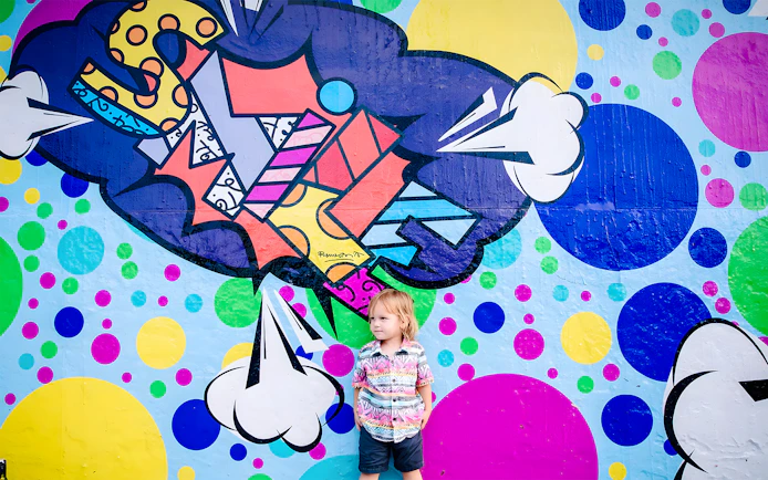 Colorful graffiti mural at Wynwood Walls, Miami, with a child standing in front.