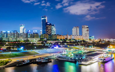Han River night cruise with Seoul skyline illuminated, featuring modern skyscrapers.