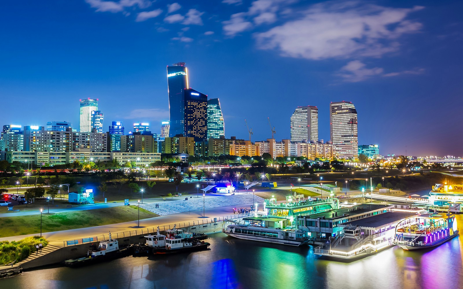 Han River night cruise with Seoul skyline illuminated, featuring modern skyscrapers.