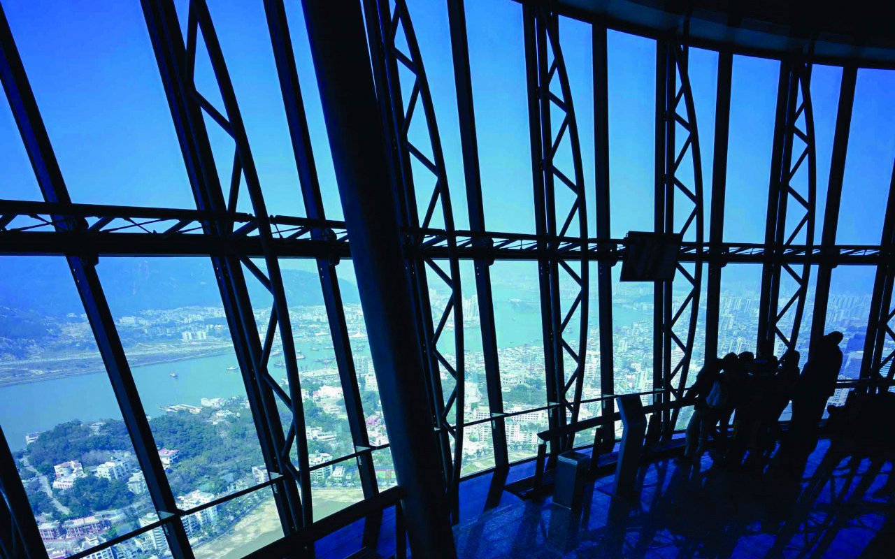 Tourists viewing cityscape from Macau Tower Observation Deck.