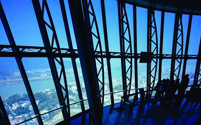 Tourists viewing cityscape from Macau Tower Observation Deck.