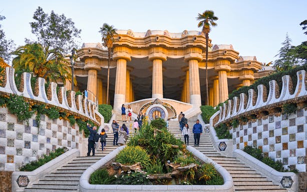 Park Güell entrance with mosaic tiles and columns in Barcelona.