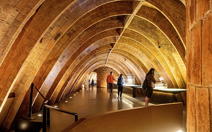 Casa Mila attic with visitors exploring Gaudi's architectural arches in Barcelona.