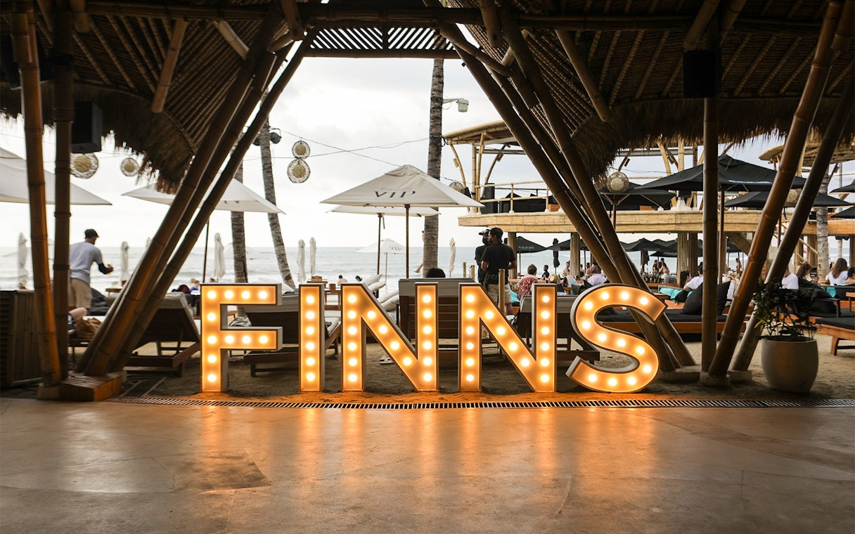 Finns Beach Club entrance with illuminated sign, Bali beachfront view.