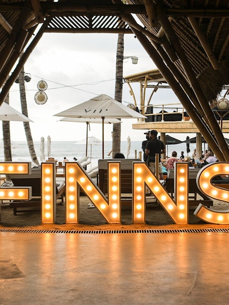 Finns Beach Club entrance with illuminated sign, Bali beachfront view.