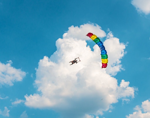 Two men paragliding in the sky with a colorful parachute.