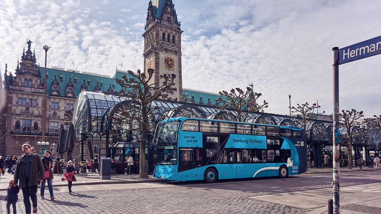 Hamburg Hop-On Hop-Off bus at a stop near historic St. Michael's Church.