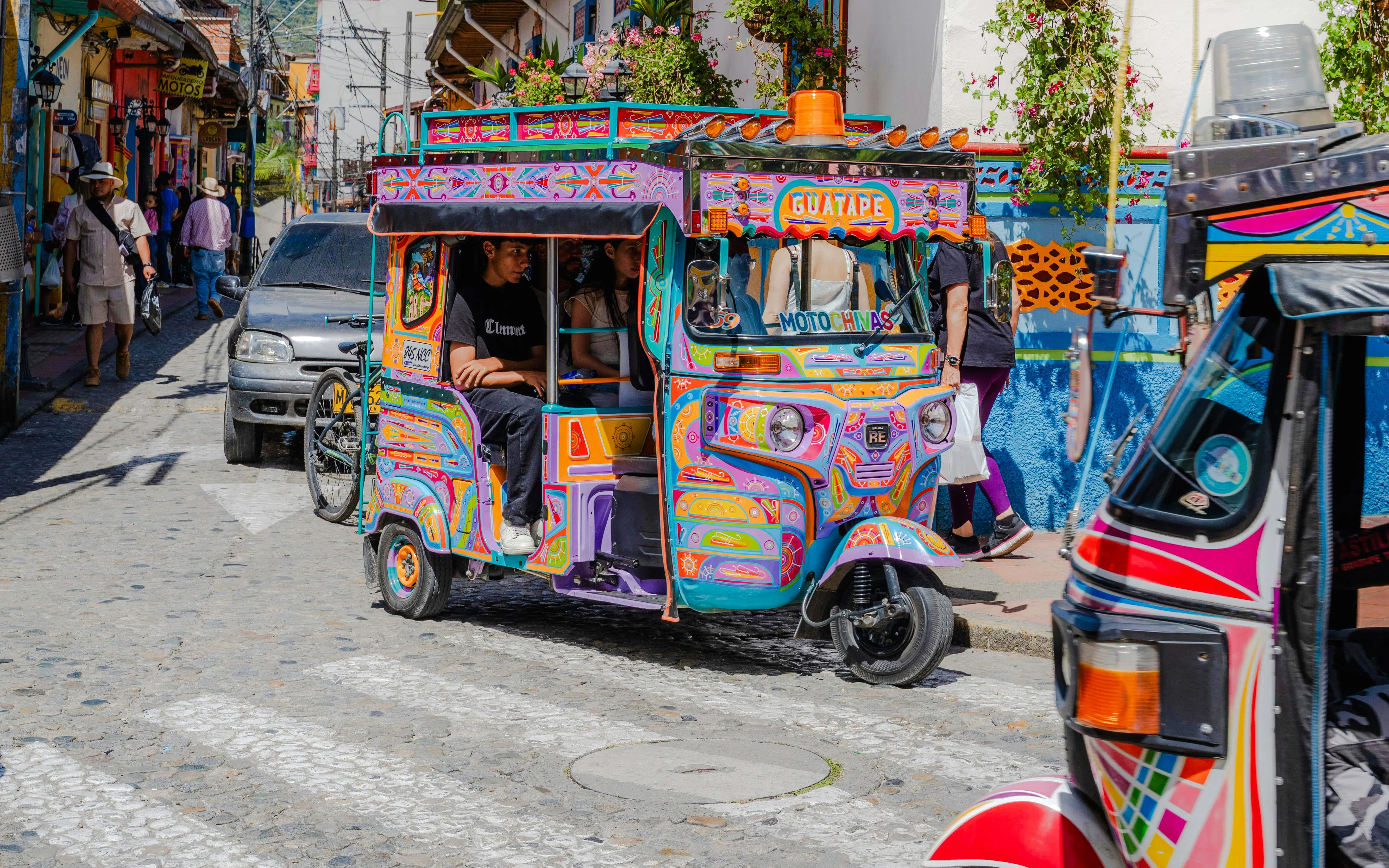 Colorful motochiva driving on a cobblestone street in Guatapé, Antioquia, Colombia.