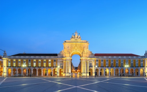 Arco da Rua Augusta in Lisbon at dusk, with illuminated arch and surrounding buildings.