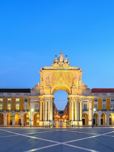 Arco da Rua Augusta in Lisbon at dusk, with illuminated arch and surrounding buildings.