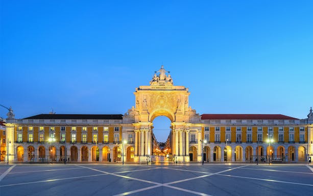Arco da Rua Augusta in Lisbon at dusk, with illuminated arch and surrounding buildings.