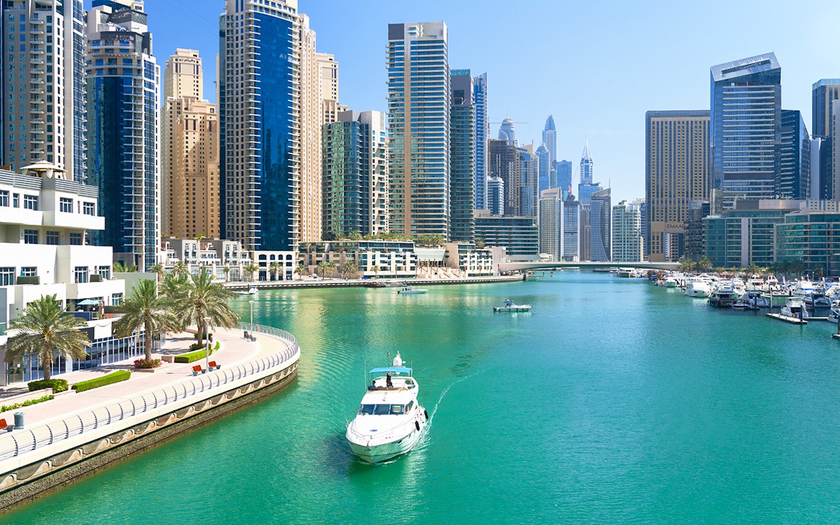 Yacht cruising through Dubai Marina with skyscrapers in the background.