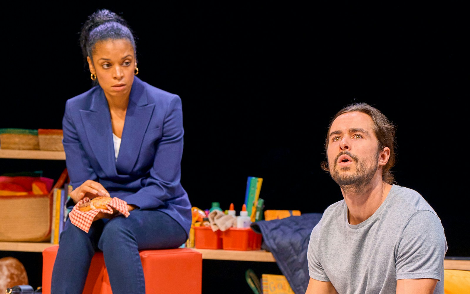 Two actors performing a scene from the play "Eureka Day" on stage.