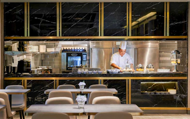 Chef preparing food at Plaza Premium Lounge kitchen counter.