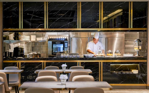 Chef preparing food at Plaza Premium Lounge kitchen counter.