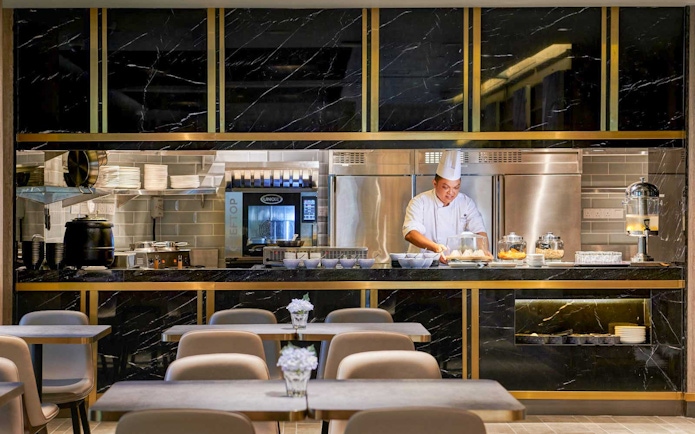 Chef preparing food at Plaza Premium Lounge kitchen counter.