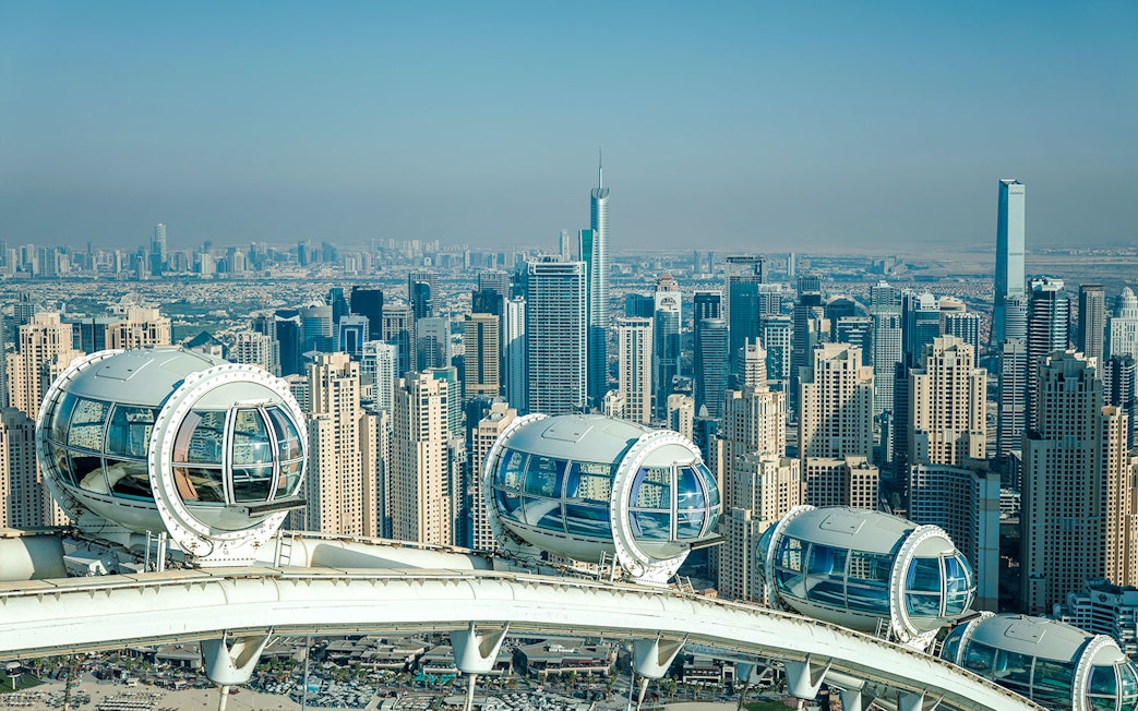 Ain Dubai pods overlooking Dubai skyline with skyscrapers in the background.