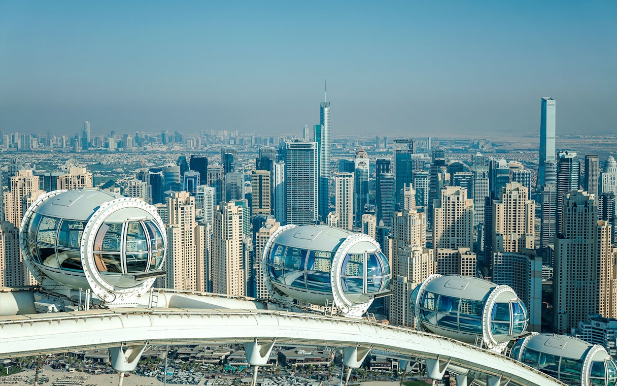 Ain Dubai pods overlooking Dubai skyline with skyscrapers in the background.