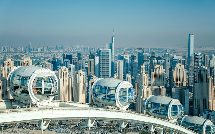 Ain Dubai pods overlooking Dubai skyline with skyscrapers in the background.