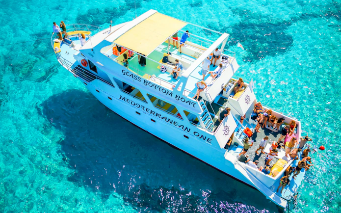 Glass-bottom boat with tourists in Blue Lagoon, Paphos, Cyprus.