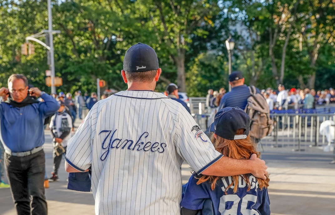 Father and daughter in Yankees jerseys outside stadium before New York Yankees vs Boston Red Sox game.