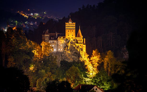 Dracula's Castle illuminated at night during Halloween tour in Transylvania.