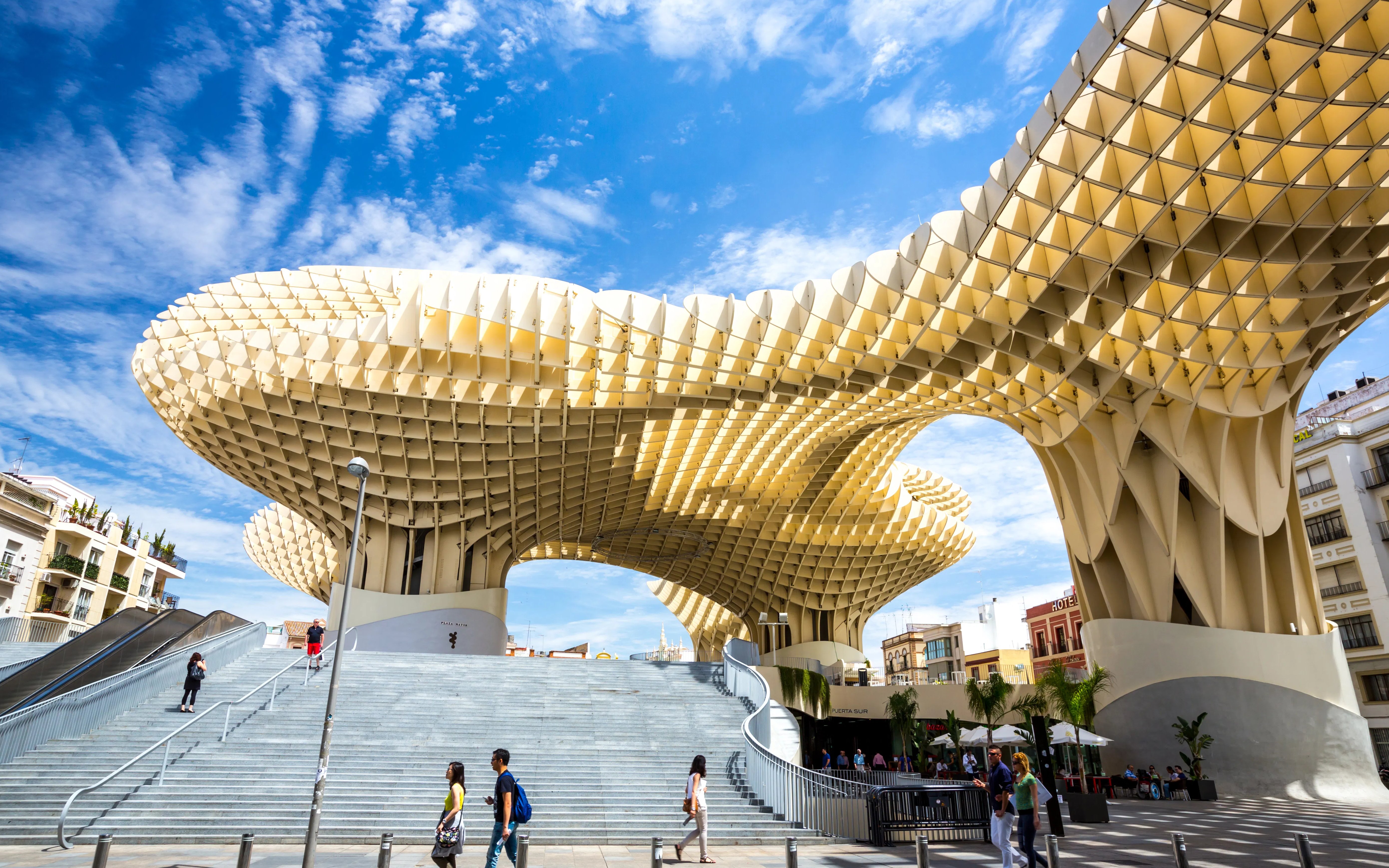 Metropol Parasol wooden structure in Plaza de la Encarnación, Seville, Spain, with people walking below.