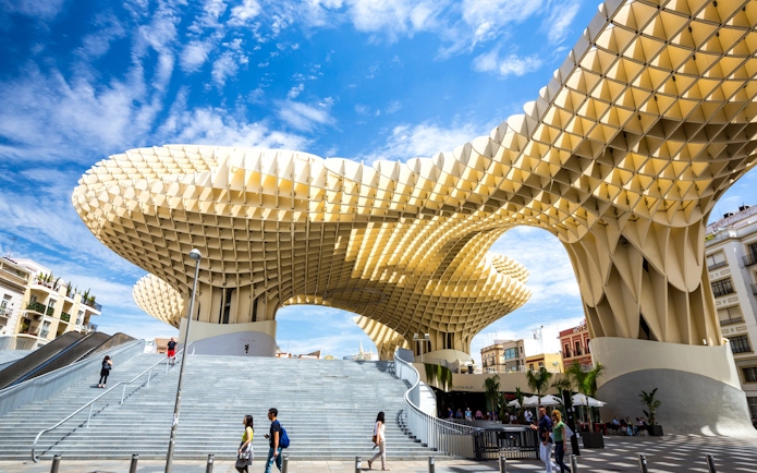 Metropol Parasol wooden structure in Plaza de la Encarnación, Seville, Spain, with people walking below.